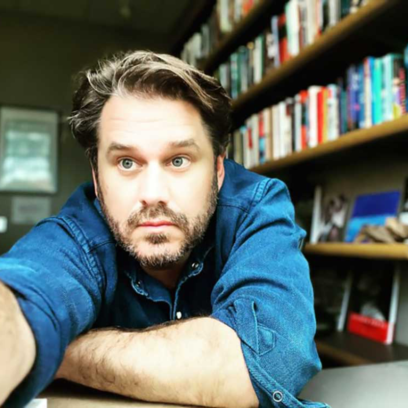 Musician sits in profile with guitar resting on lap.